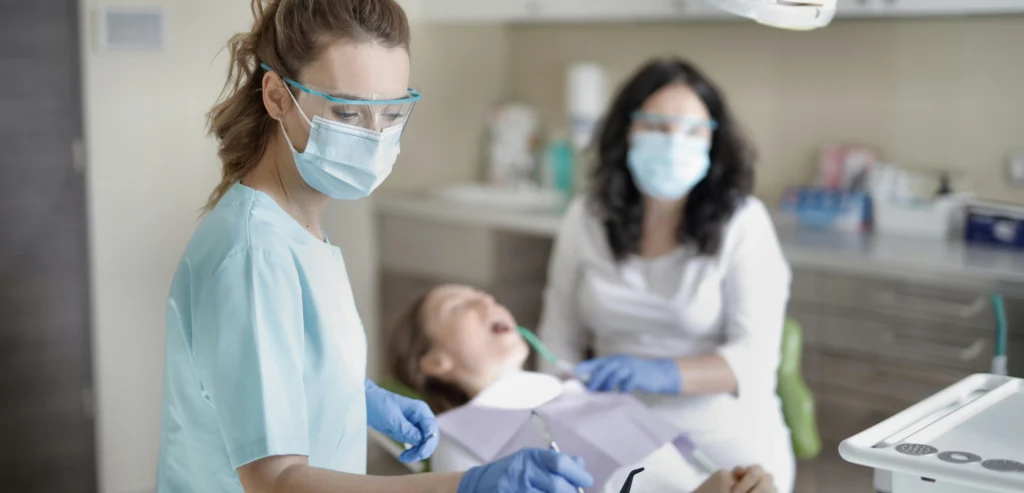 Dentista e assistente a realizar procedimento numa paciente na clínica dentária.