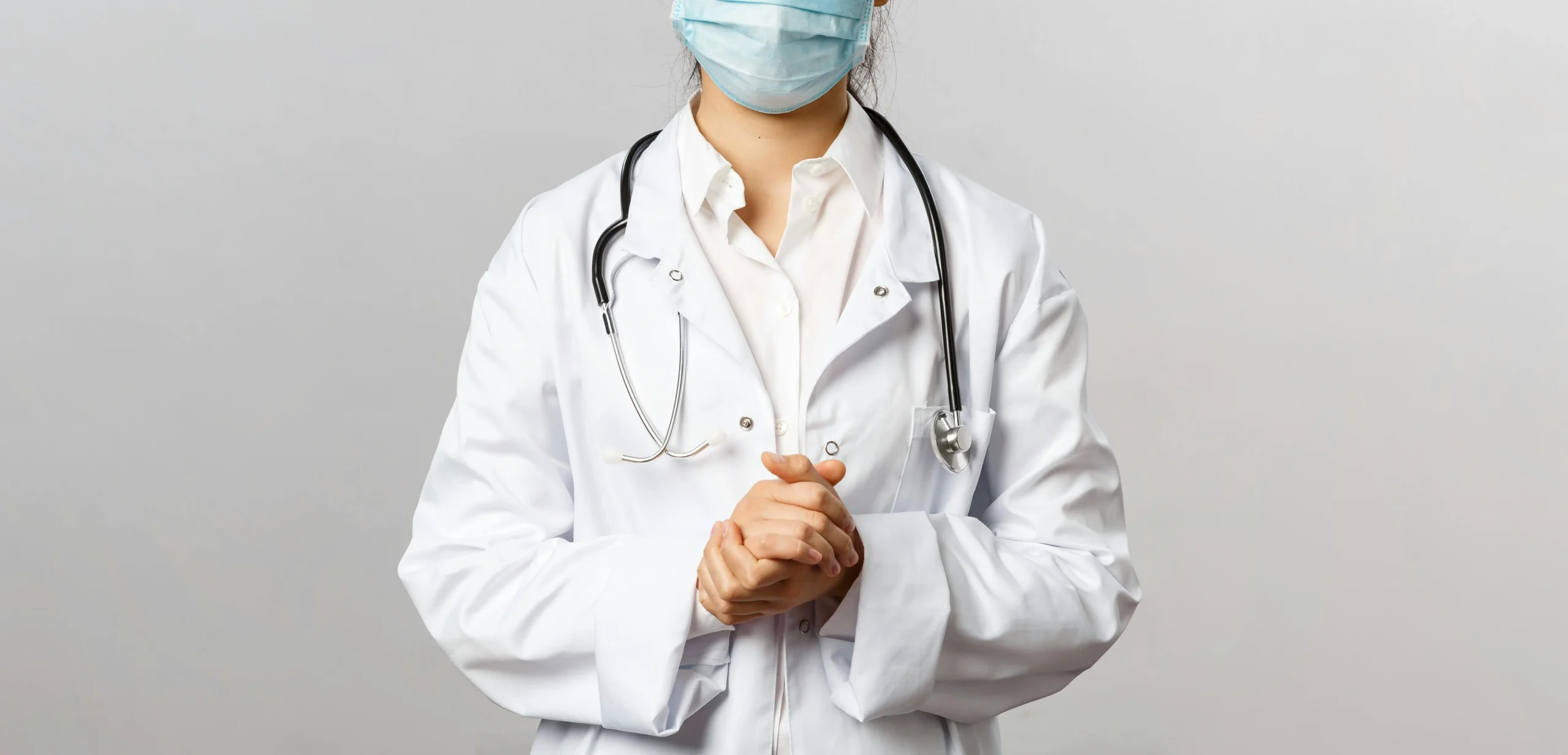 Médica com máscara e estetoscópio em clínica.