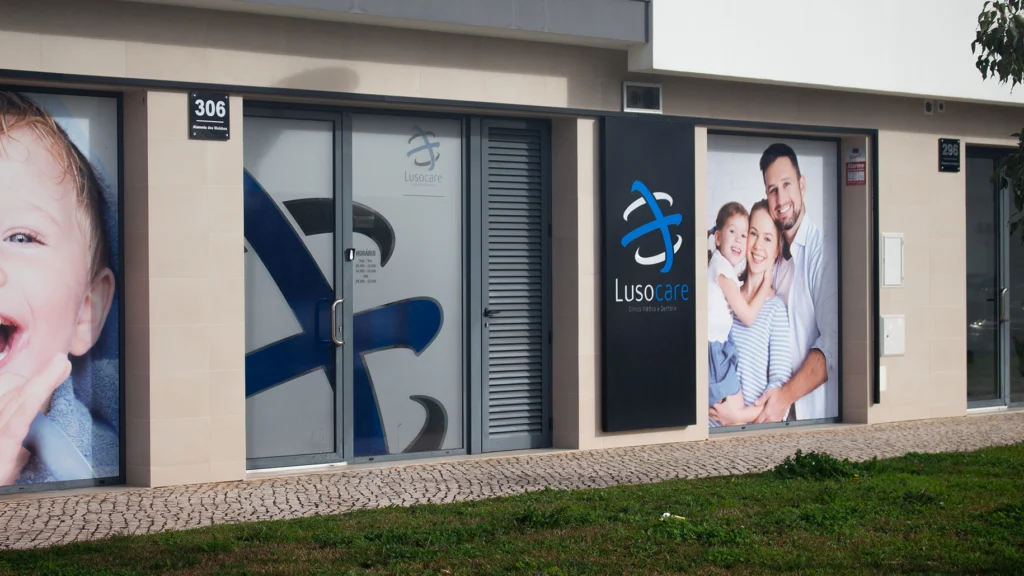 Fachada da clínica dentária Lusocare com imagens de pacientes e logótipo.