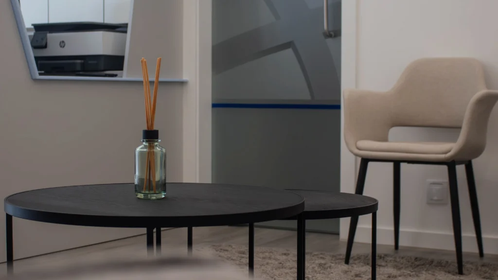 Sala de espera com mesa redonda e cadeira acolchoada.