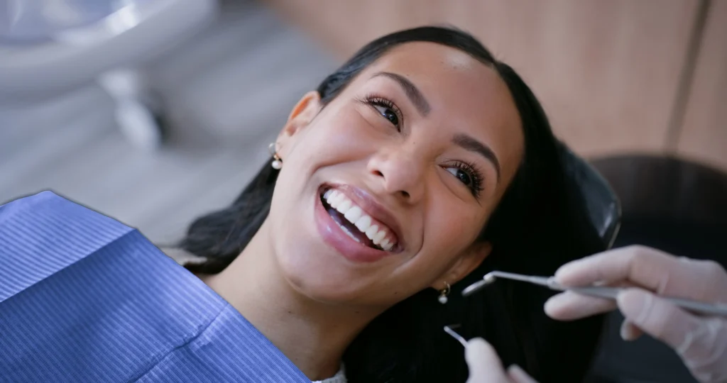 Paciente sorri durante exame dentário com instrumento de diagnóstico.