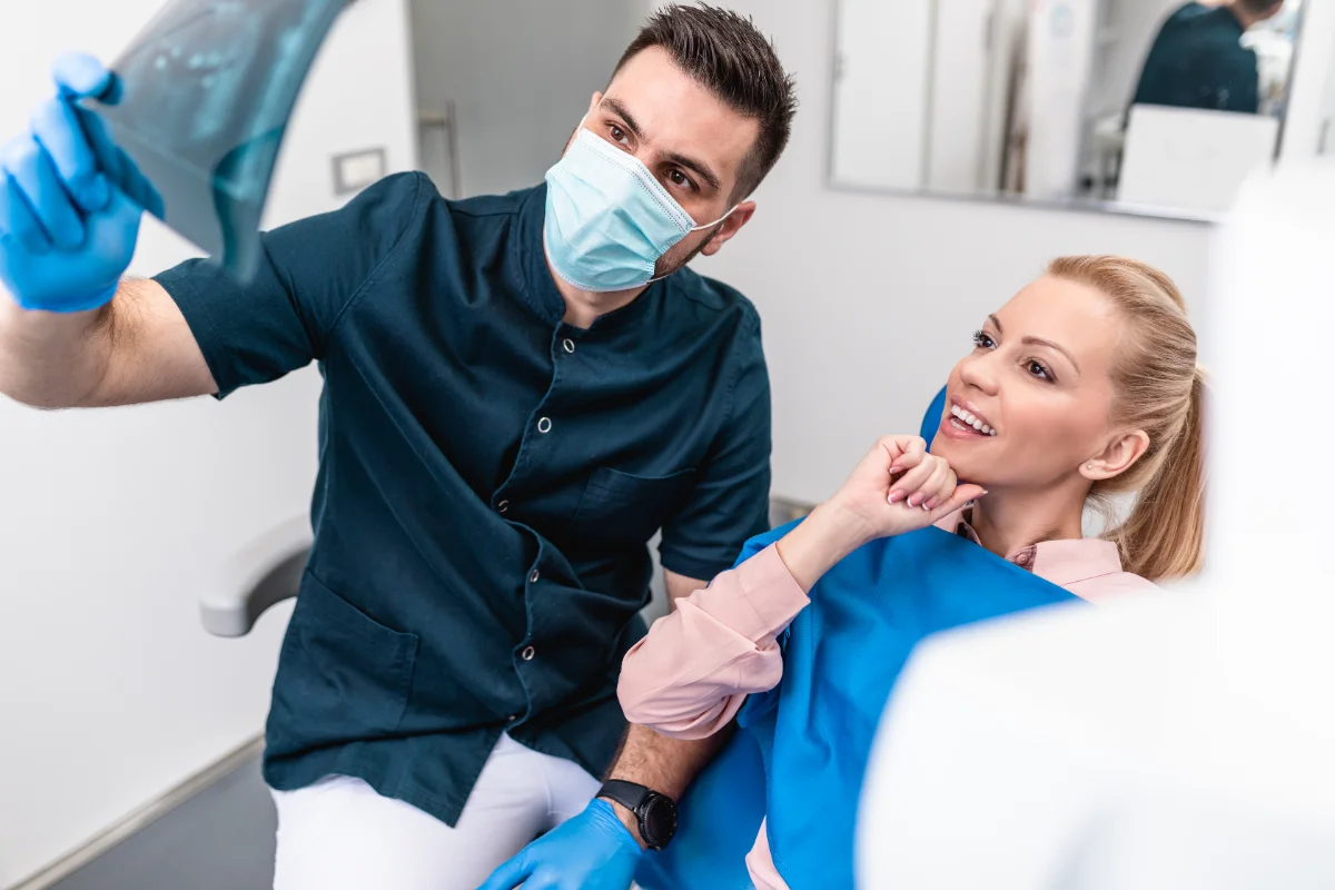 Dentista a mostrar raio-x a paciente sorridente na clínica.