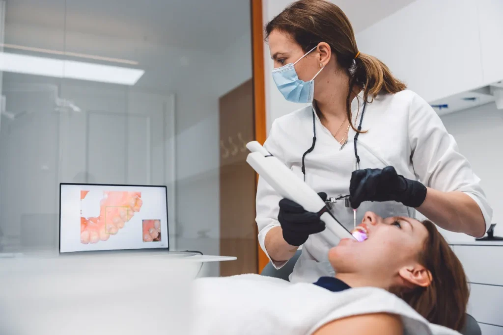 Dentista a usar equipamento de branqueamento dentário numa paciente.